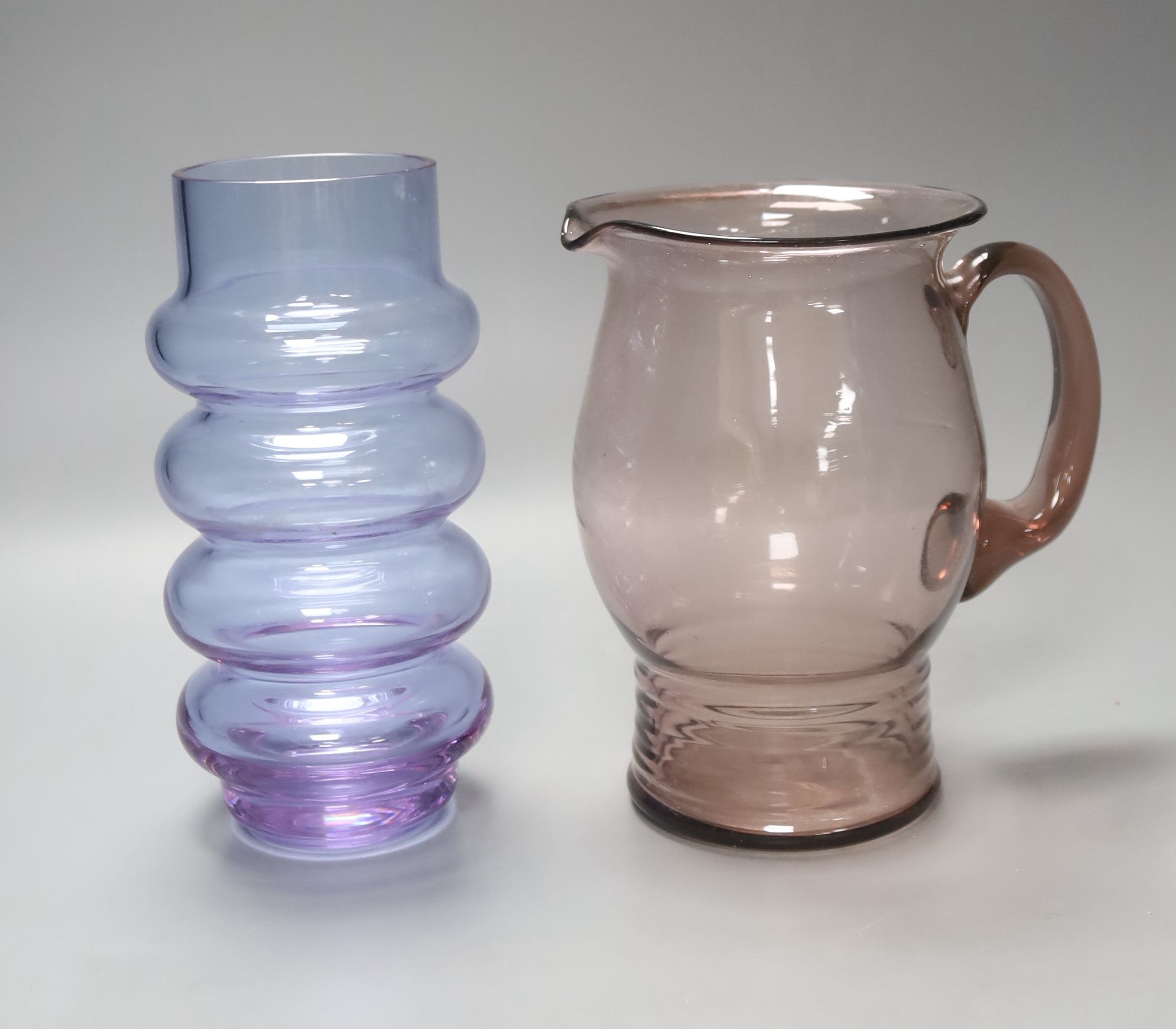 An Art glass pale amethyst jug with ribbed foot and a pale blue glass cylindrical ring-form vase, height 21cm